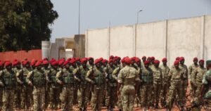 Grupo de militares de uniforme e boina vermelha reunidos ao ar livre.