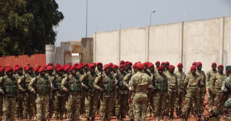 Grupo de militares de uniforme e boina vermelha reunidos ao ar livre.