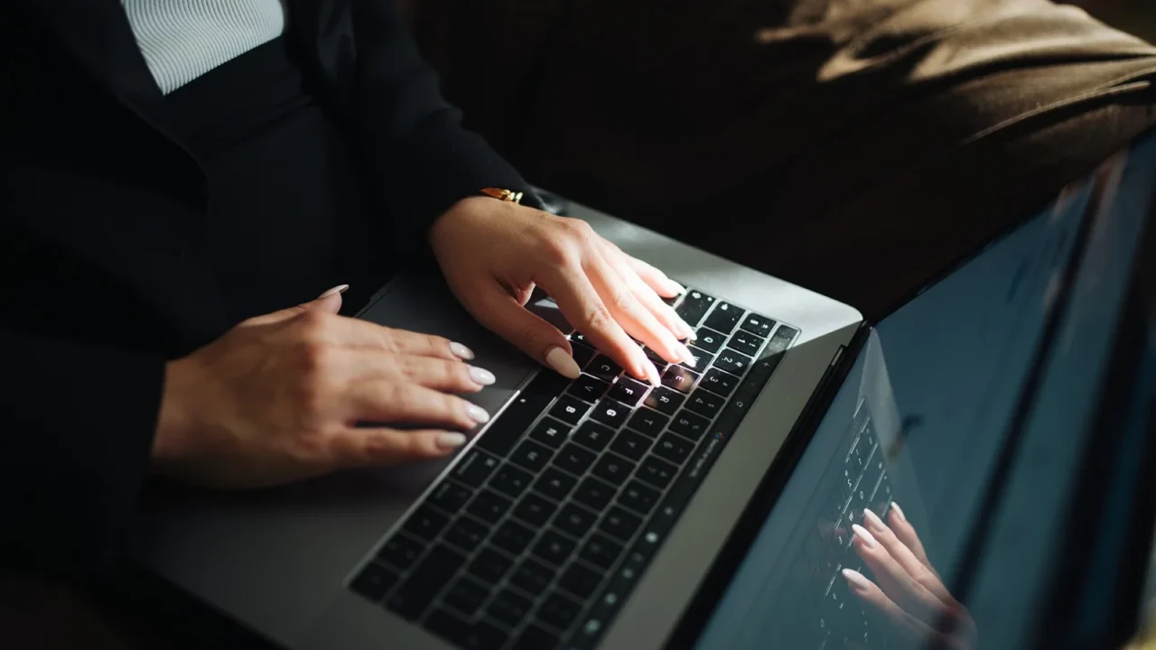 Mãos de uma pessoa a digitar no teclado de um computador portátil.