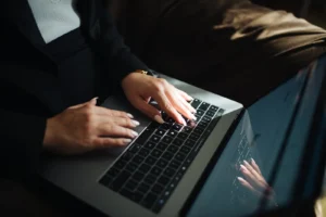 Mãos de uma pessoa a digitar no teclado de um computador portátil.